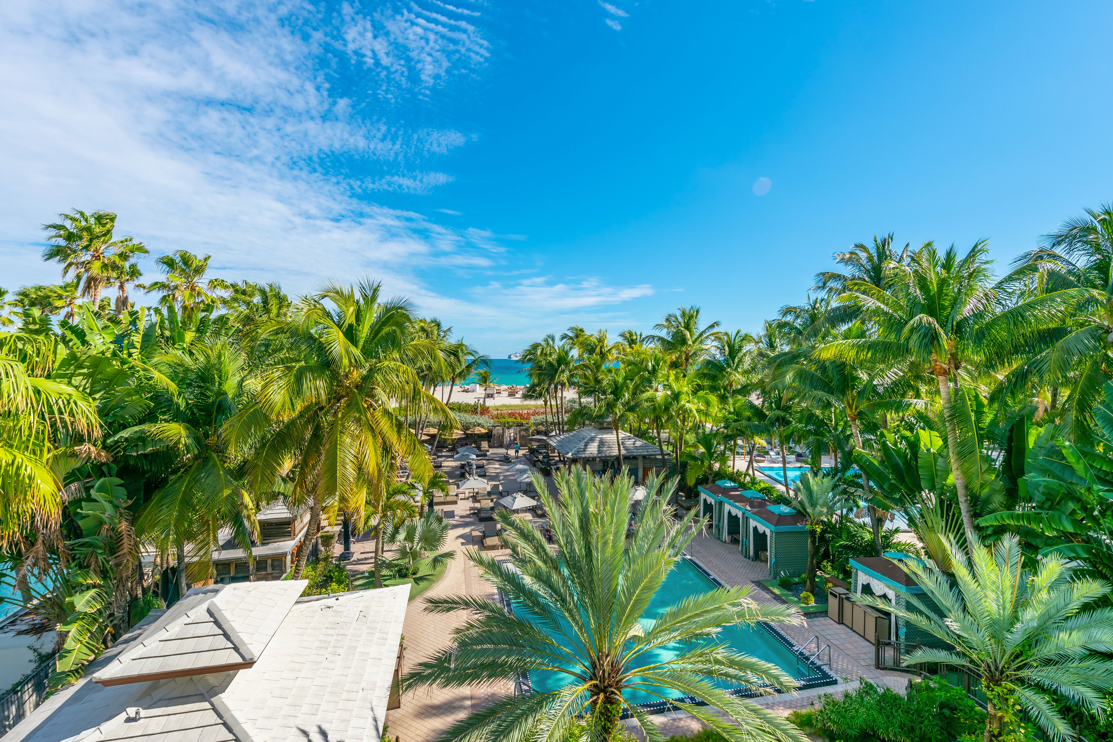 A resort with a pool area surrounded by palm trees and lounge chairs.