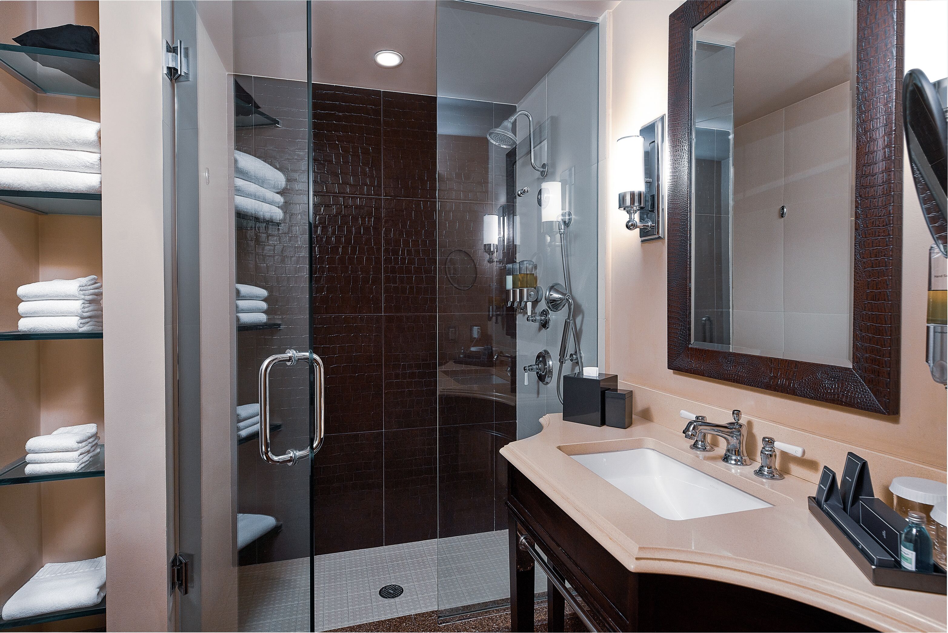 A modern bathroom with a glass-enclosed shower, a large mirror, and a vanity with a sink and towel racks.