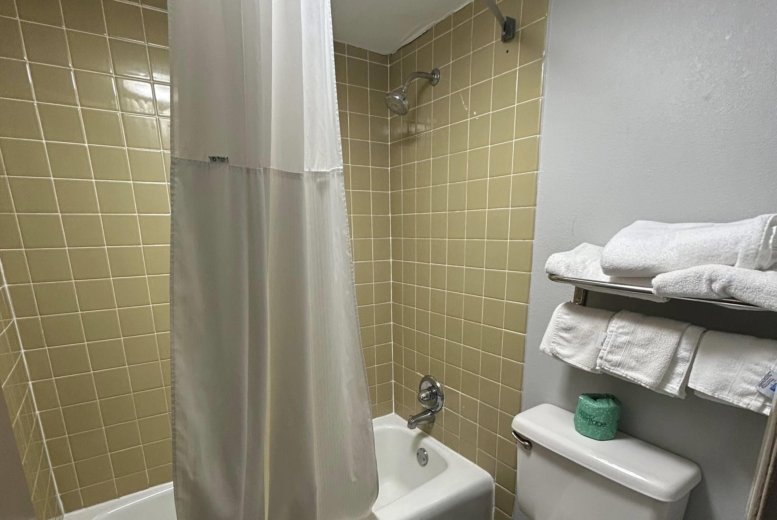 Um banheiro com chuveiro, vaso sanitário e porta-toalhas com toalhas.