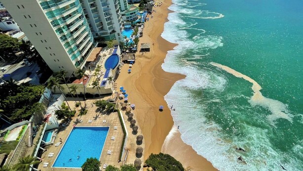 Un resort con piscina, playa y vista al océano.