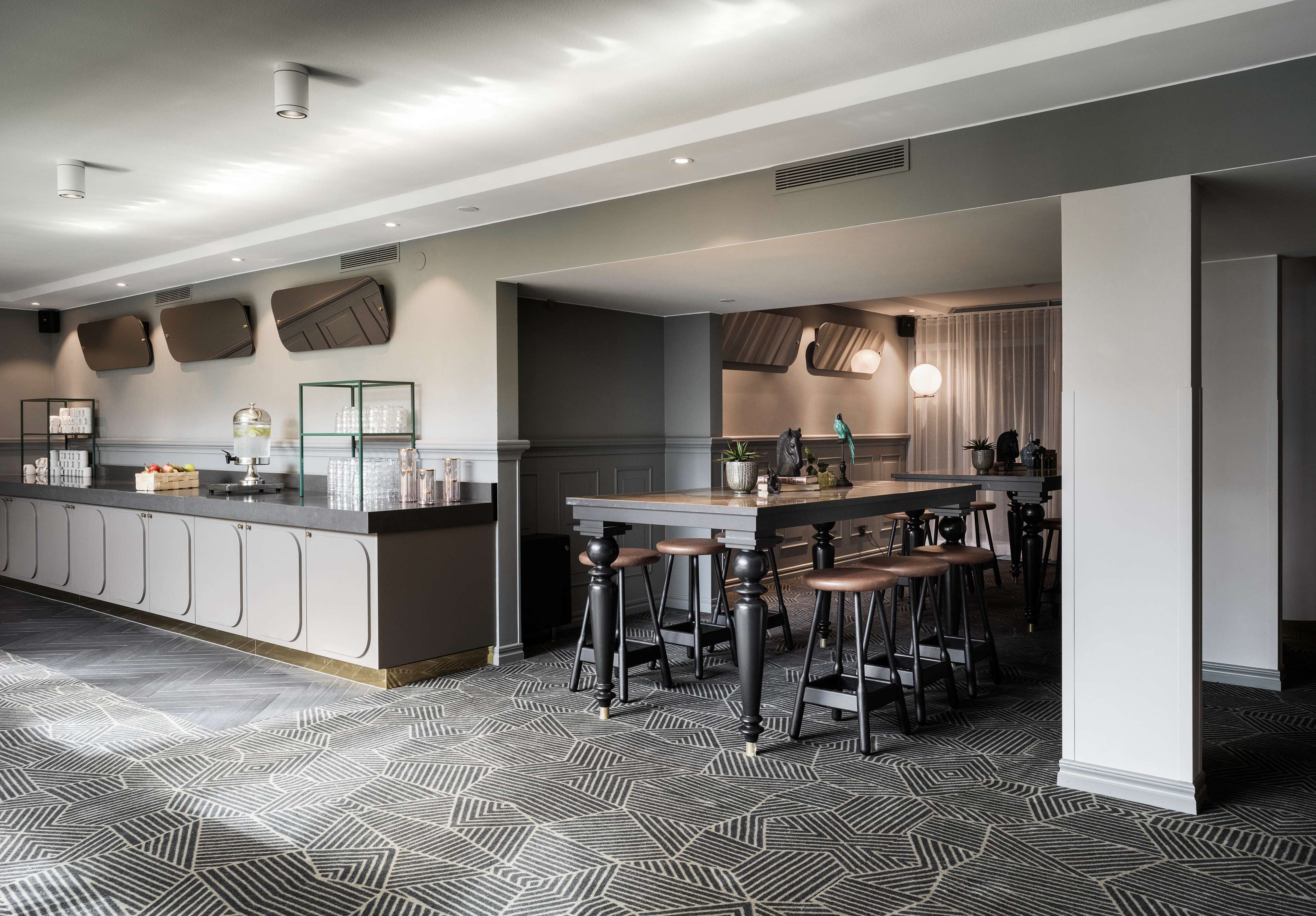 A modern kitchen with a central island, bar stools, and a patterned floor.