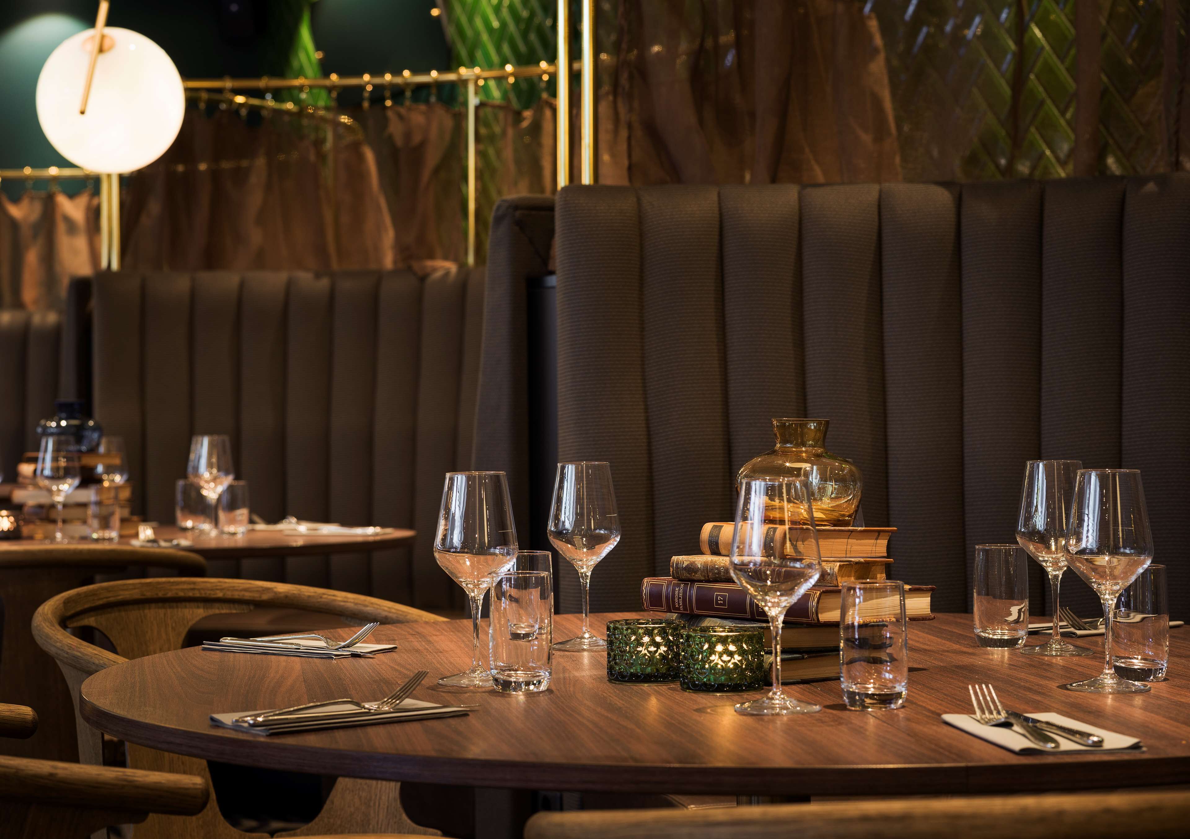 Un ambiente de restaurante con mesas dispuestas para comer, que incluye copas de vino, cubiertos y objetos decorativos.
