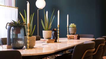 Uma mesa de jantar com plantas em vasos, velas e livros.
