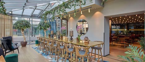 Un espace intérieur moderne doté d’une longue table à manger, de chaises et d’un coin bar.
