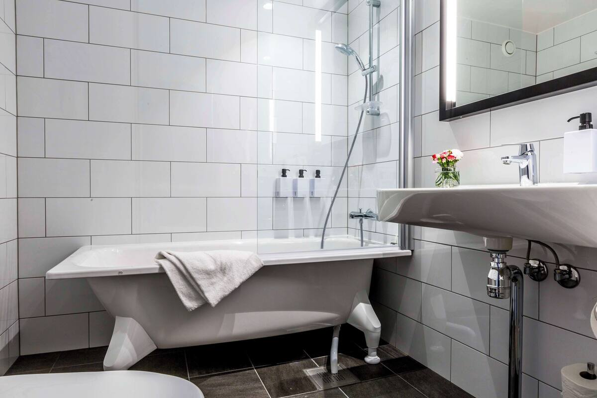 A modern bathroom with a freestanding bathtub, a sink with a mirror, and a shower area.