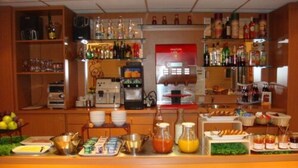 Un espace bar avec des étagères remplies de bouteilles, un appareil à café et une variété de produits alimentaires exposés sur le comptoir.