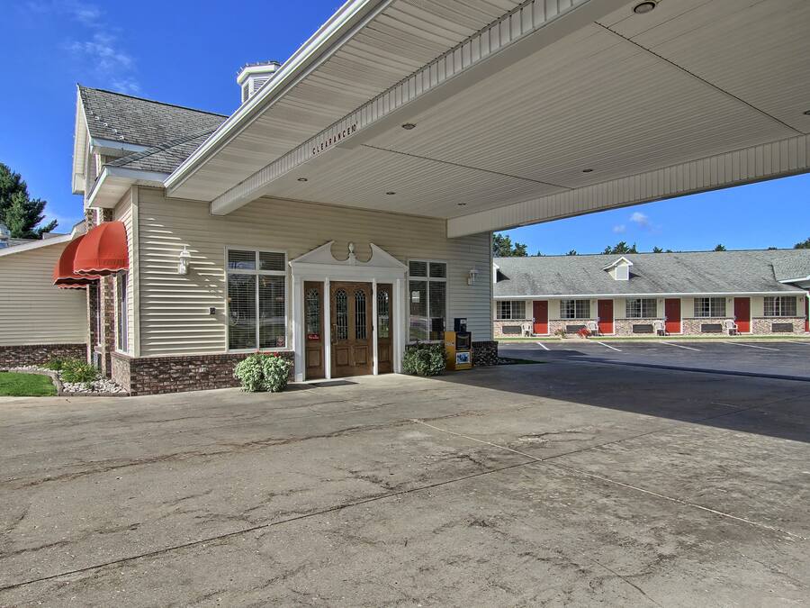 A motel with a covered entrance, a parking lot, and a row of rooms with red awnings.