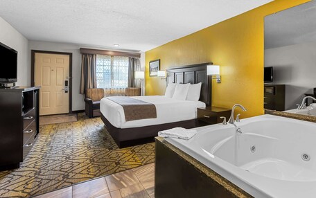 A hotel room with a large bed, a separate bathroom with a bathtub, a television, and a desk with a chair.
