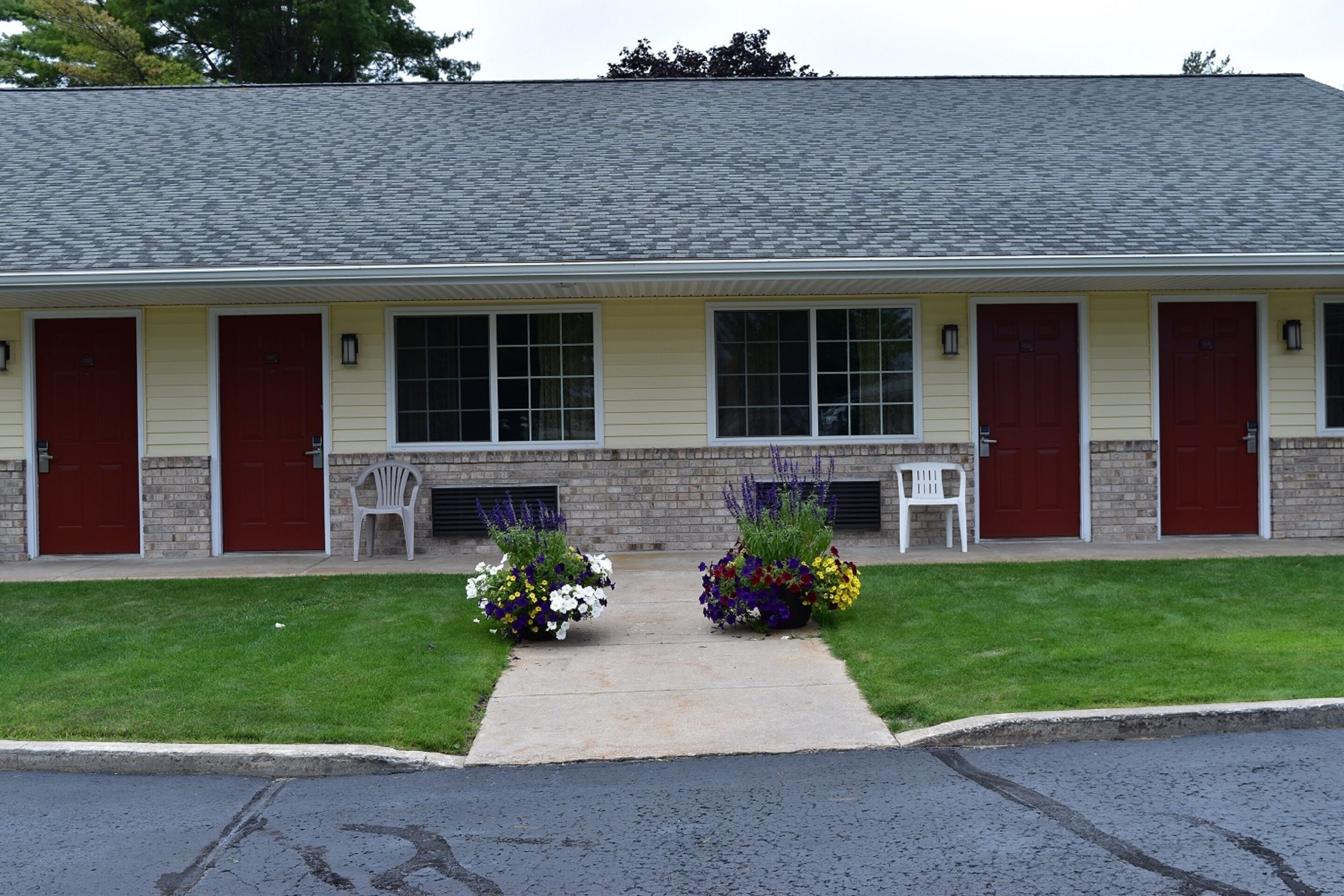 A two-story building with a flat roof, a brick facade, and a central entrance with a concrete pathway.
