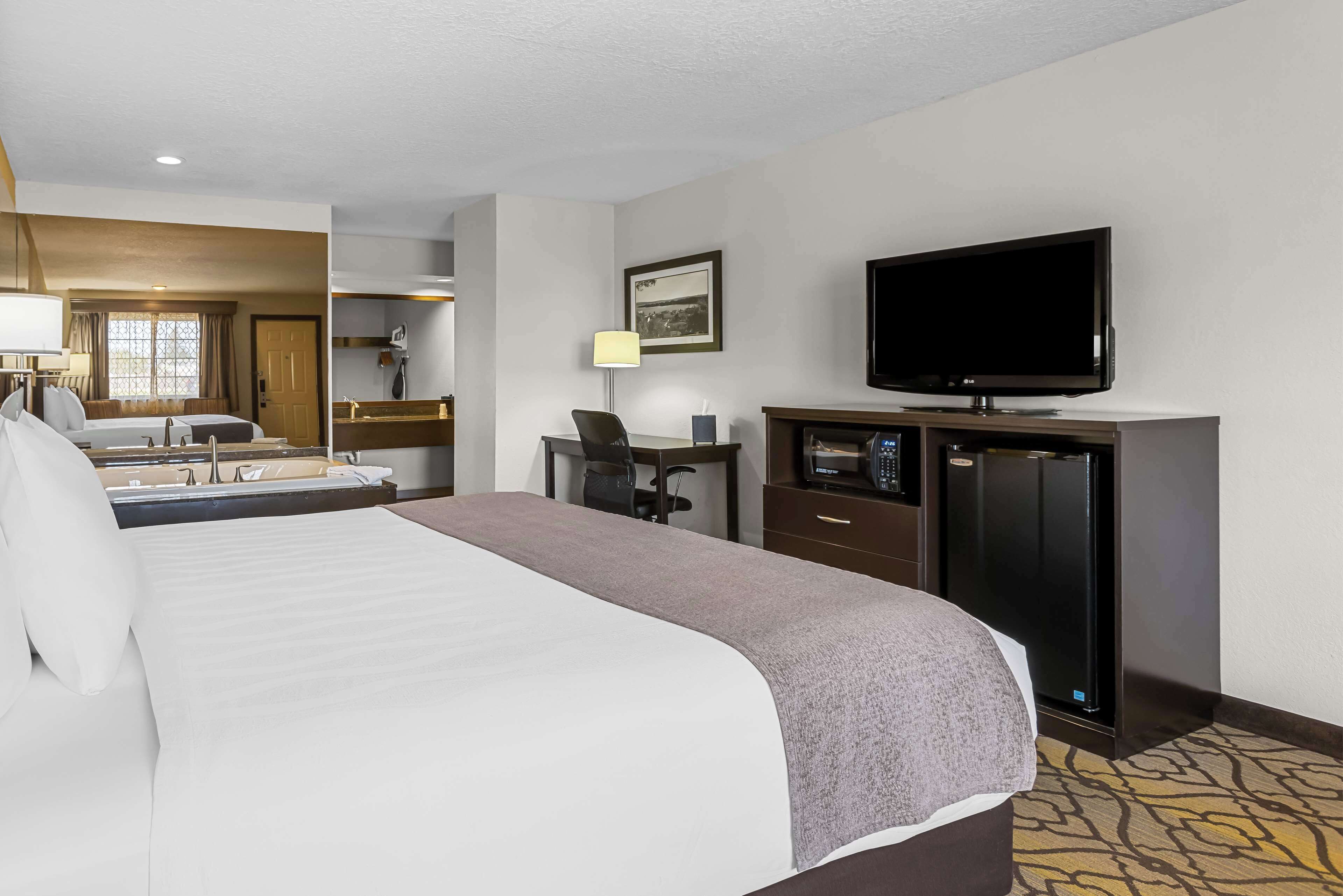 Une chambre d’hôtel avec un grand lit, un bureau avec une chaise, une télévision et un mini-bar.