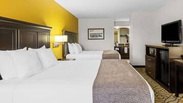 A hotel room with two beds, a television, a desk, and a bathroom visible in the background.