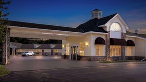 A hotel with a covered parking area, a main entrance with a door, and a visible gas station sign. - Best Western of Harbor Springs (Harbor Springs)