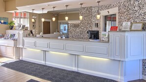 A reception area with a white counter, pendant lighting, a stone wall, and a framed certificate on the wall. - Best Western of Harbor Springs (Harbor Springs)