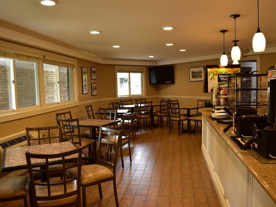 Un ristorante con diversi tavoli e sedie, un bancone con una macchina del caffè e una televisione montata a parete.