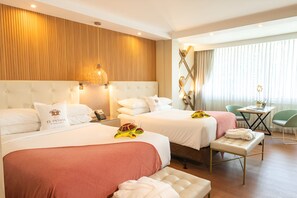 Habitación de hotel con dos camas, una pared decorativa de madera, un escritorio con una silla y vistas al exterior.