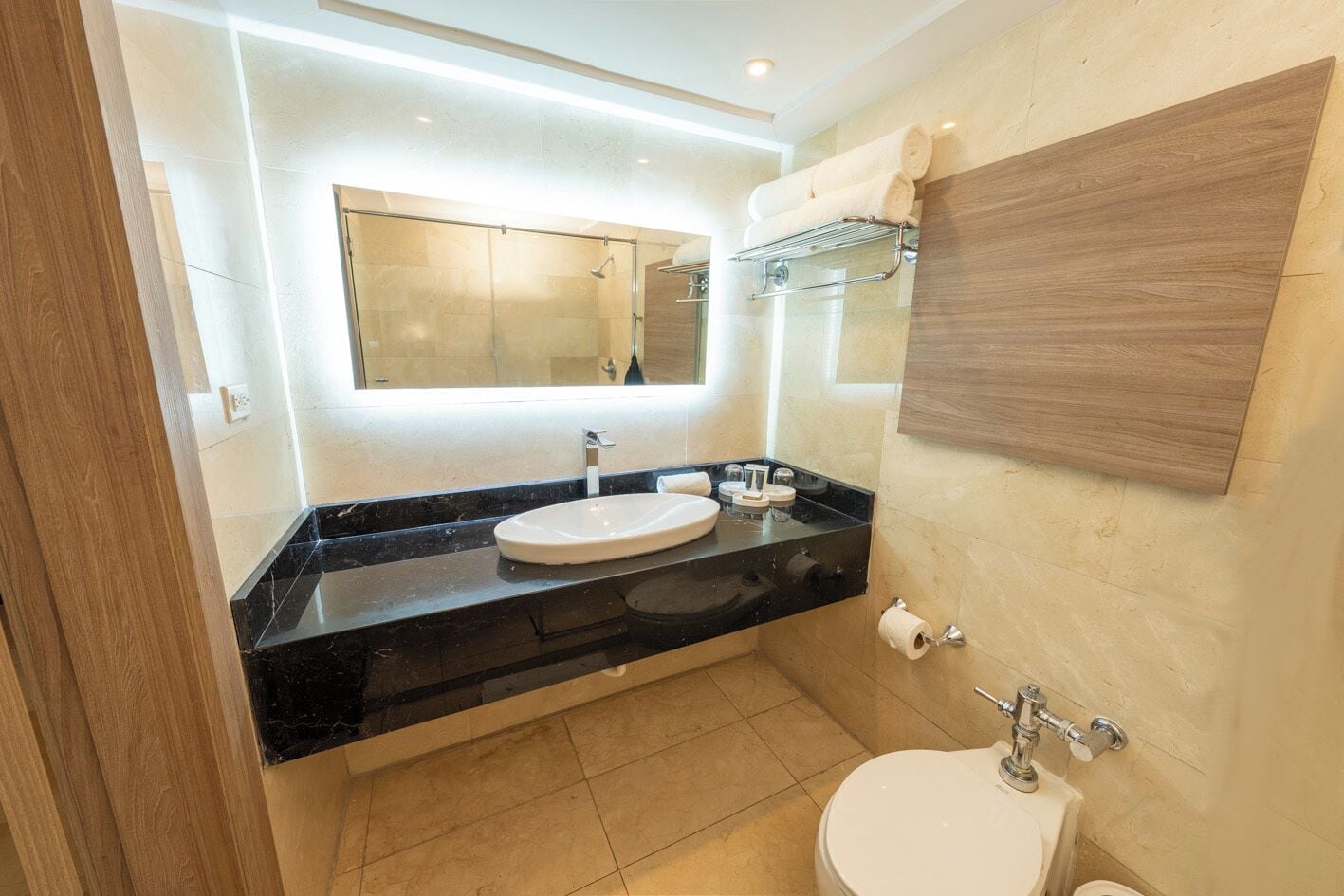 A modern bathroom with a black countertop, white sink, and a wooden vanity.