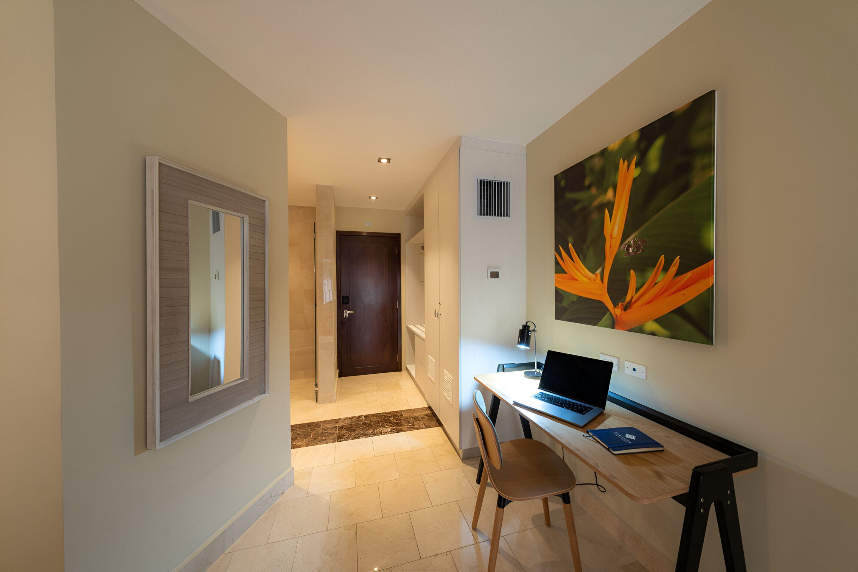 A modern hotel room with a desk, chair, and a large window.