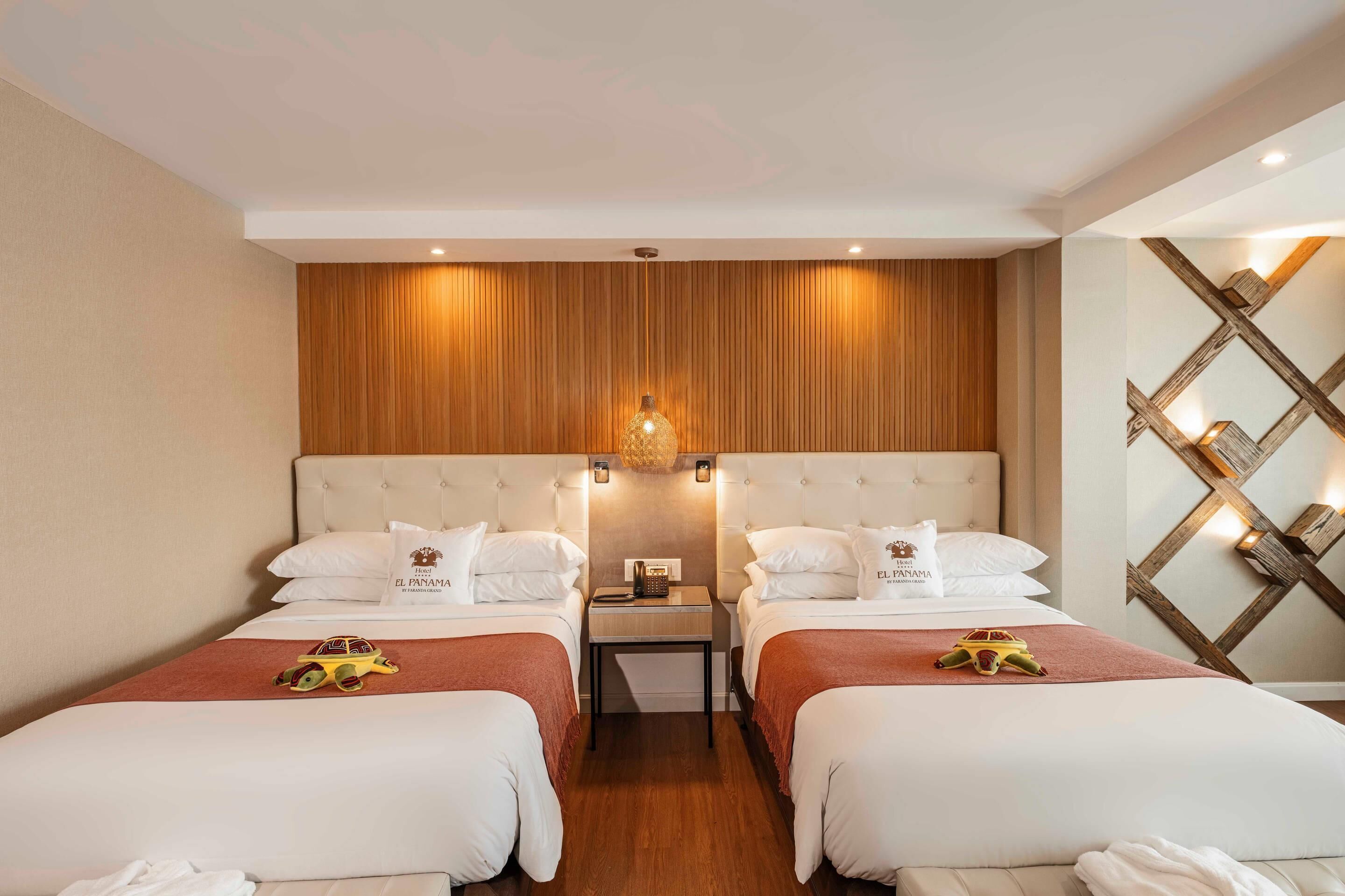 A hotel room with two beds, wooden paneling on the wall, a nightstand with a lamp, and a decorative wall piece.