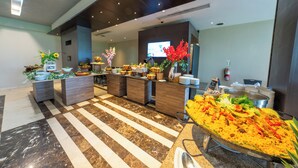 A buffet area with a variety of dishes, a long counter with food, and a seating area with tables and chairs.