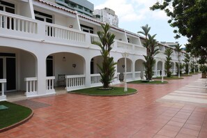 Un patio con edificios blancos, arcos y palmeras.