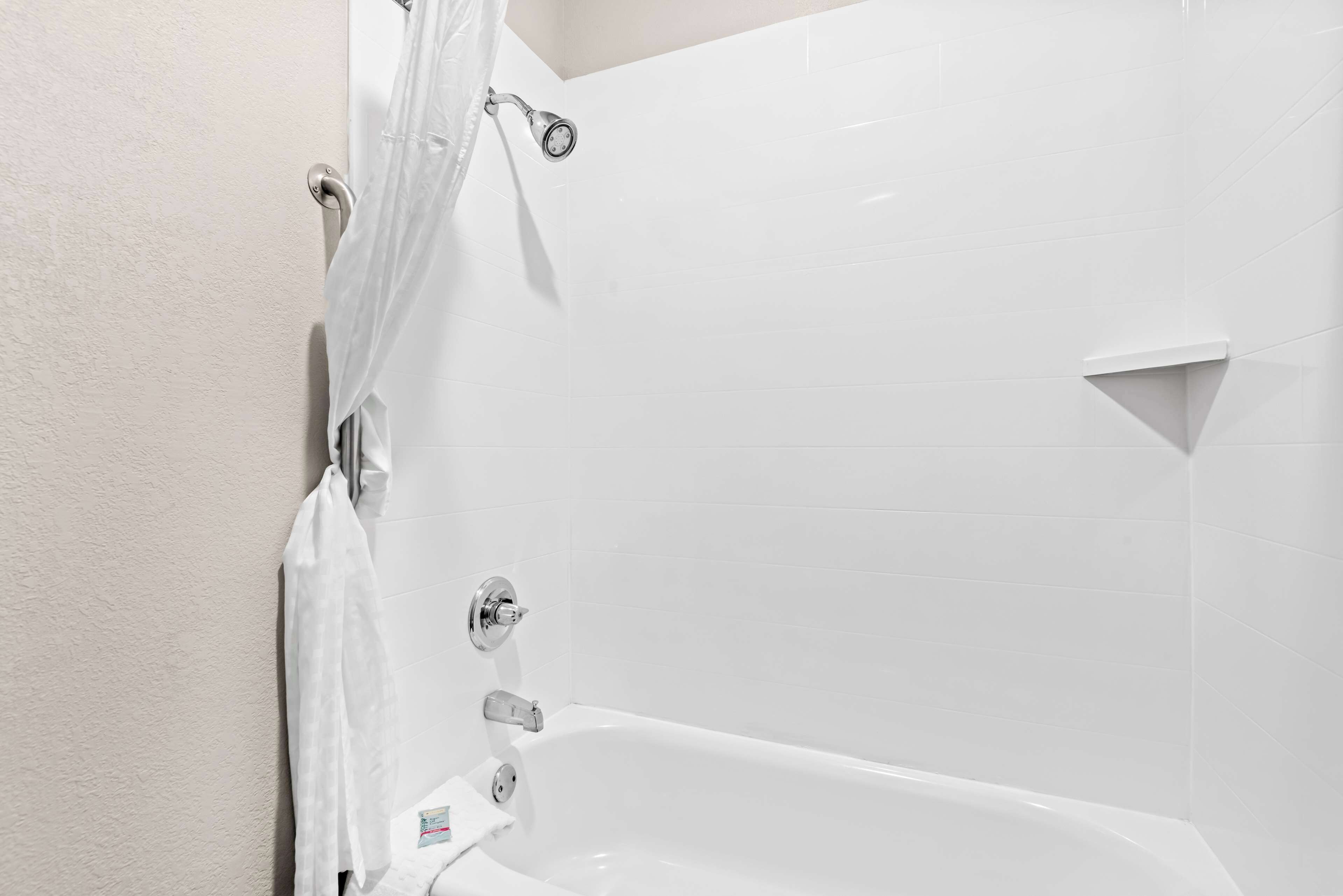 Una bañera blanca con cortina de ducha y ducha de mano.