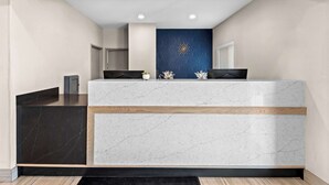 Zona de recepción con mostrador de mármol, pared decorativa azul y diseño moderno.