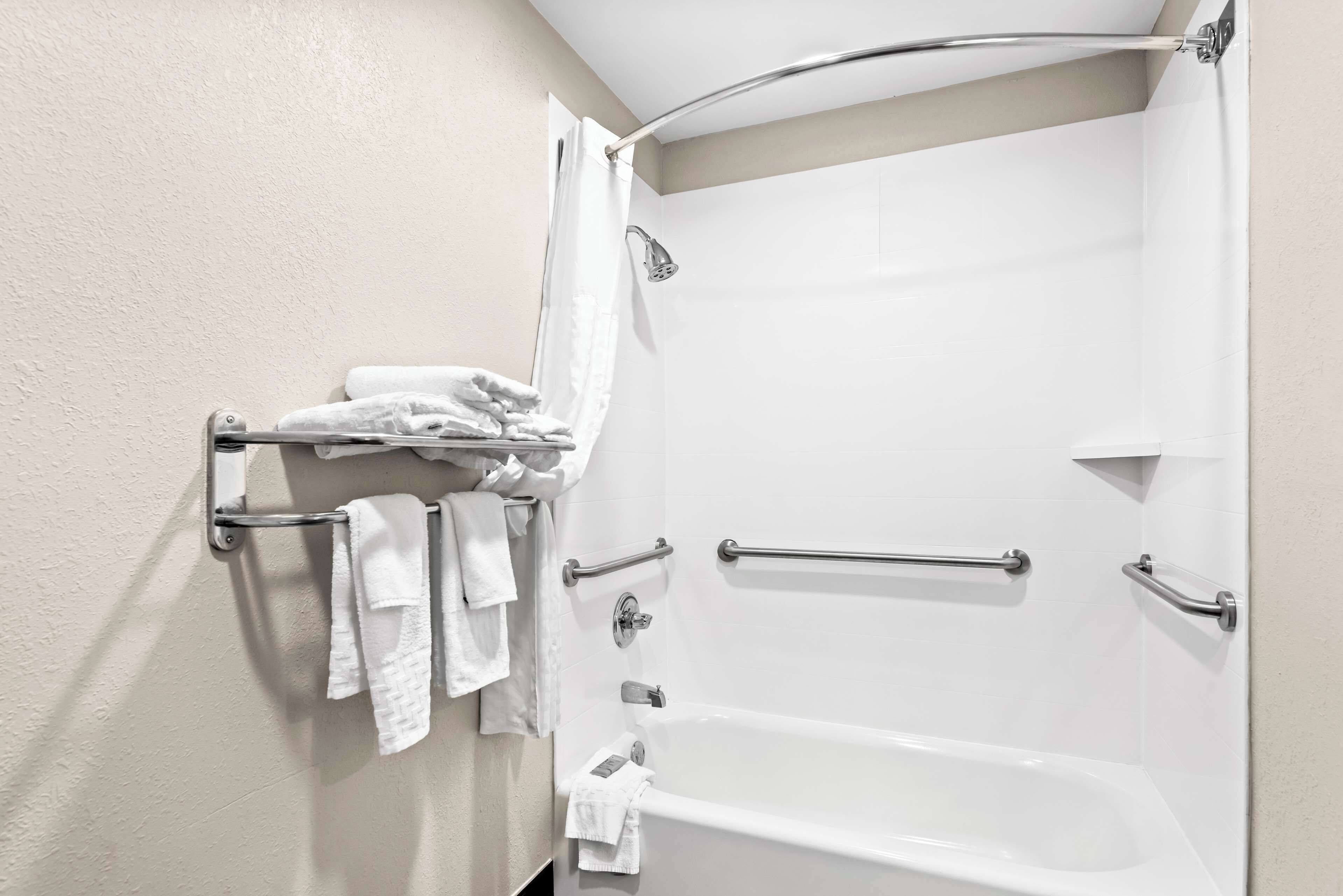 Un baño con bañera, ducha y un tendedero con toallas dobladas.