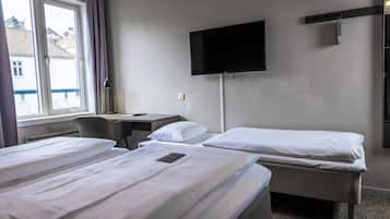 A hotel room with two beds, a desk, a chair, a TV mounted on the wall, and a window with curtains.