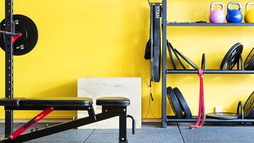 A gym with a bench, weight rack, kettlebells, and resistance bands.