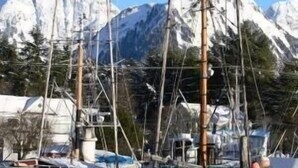 Un port de plaisance où des bateaux sont amarrés devant des montagnes enneigées.
