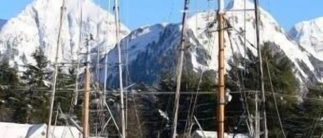 Ein Yachthafen mit vertäuten Booten vor einer schneebedeckten Bergkulisse.