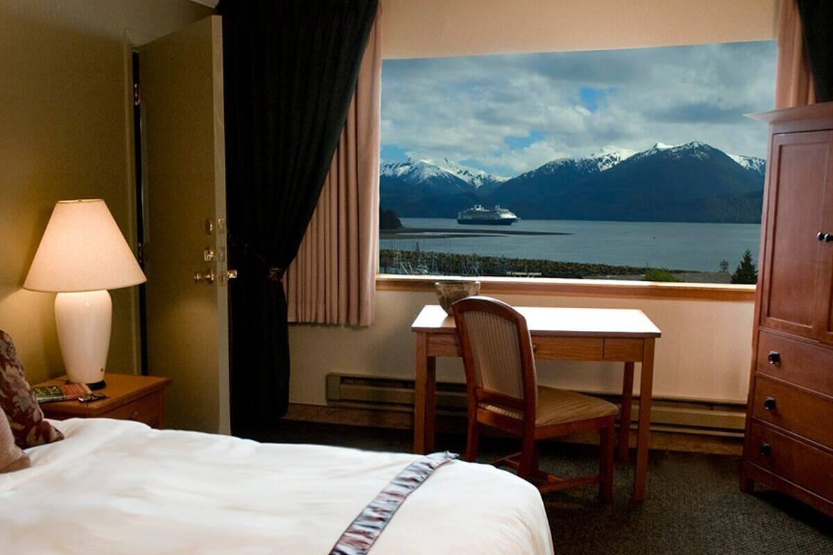 Une chambre d’hôtel avec un lit, un bureau et une vue sur les montagnes et un lac.