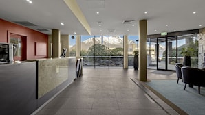 A modern reception area with a marble counter, a coffee machine, and a view of snow-capped mountains through large windows.