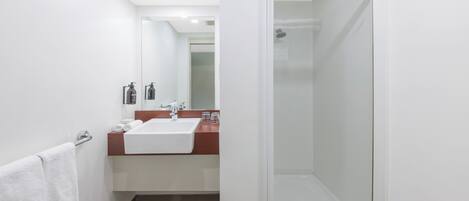 Un baño moderno con ducha acristalada, lavamanos blanco y espejo.