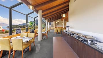 Un restaurante con vistas a las montañas y una zona de bufé con fuentes de comida.