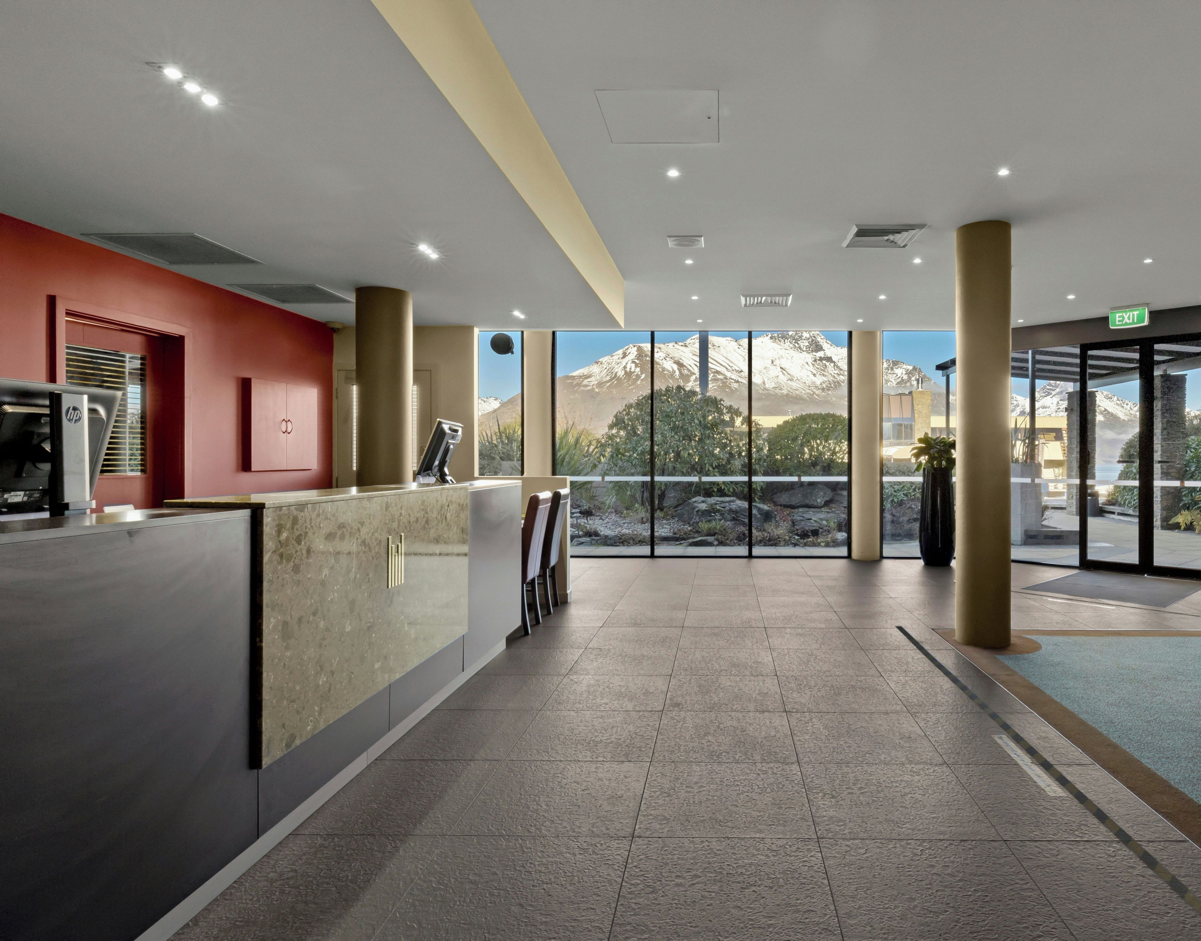A reception area with a counter, chairs, and a view of snow-capped mountains through large windows.