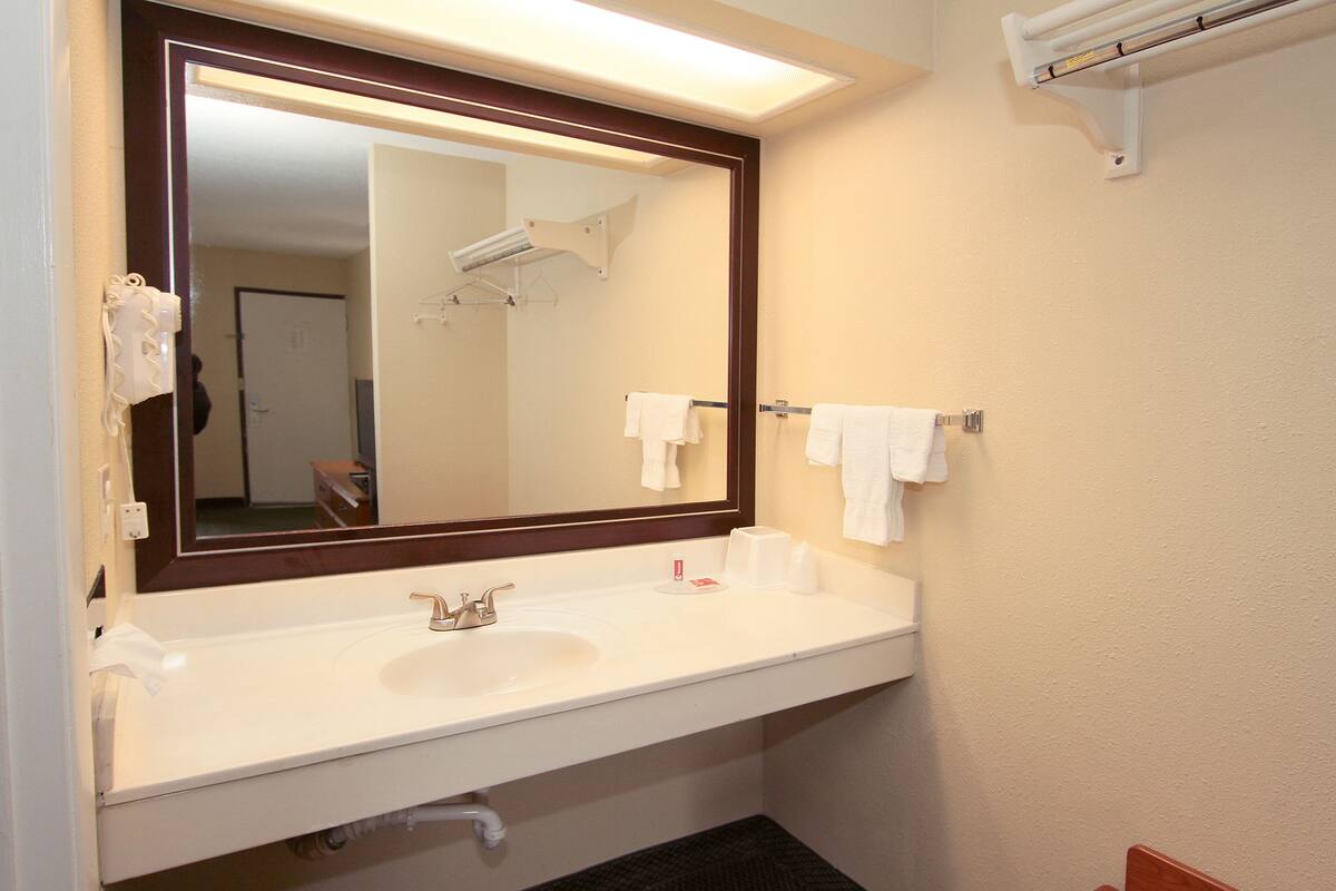 A bathroom with a white sink, a mirror, and a towel rack.