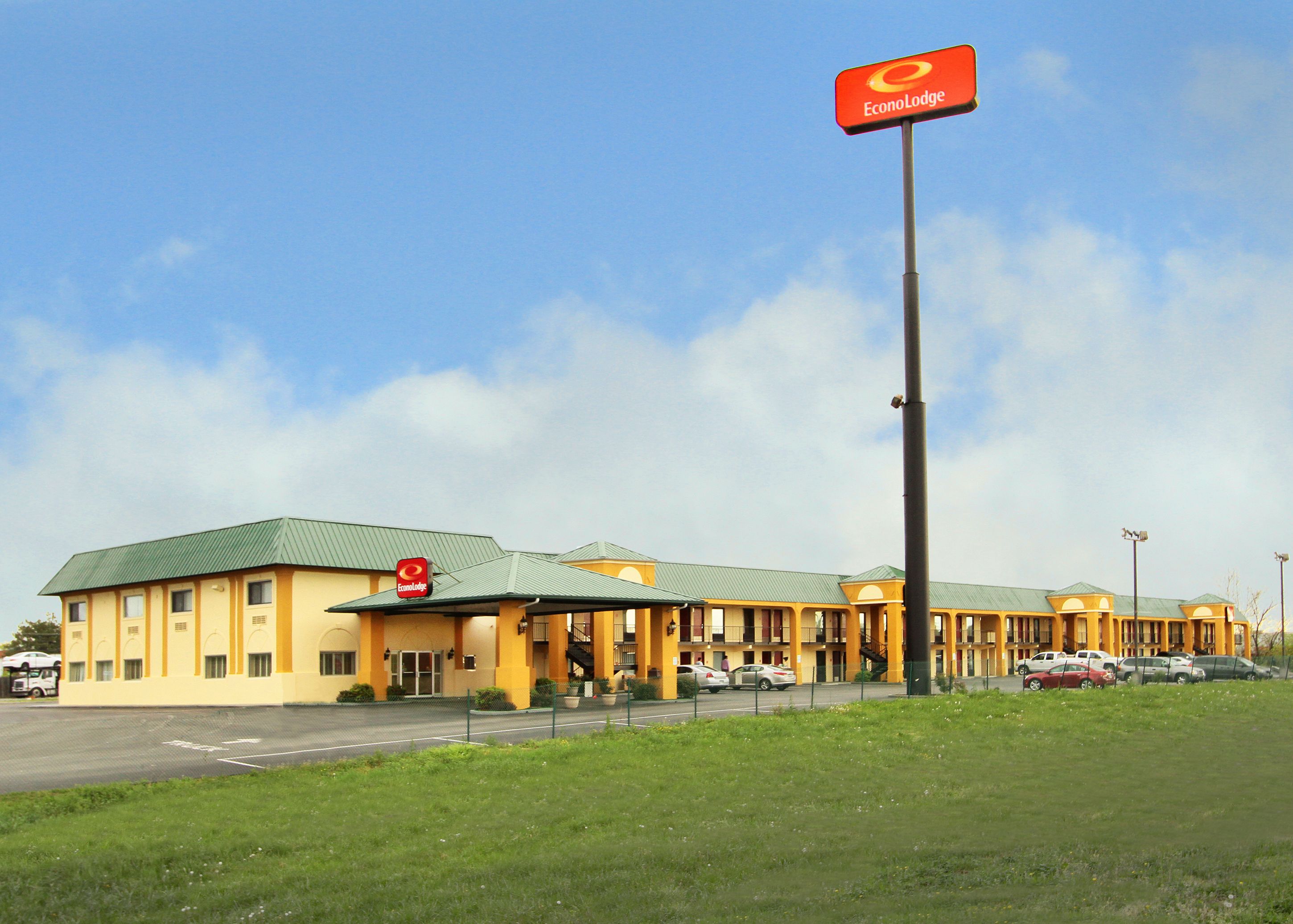 A hotel with a green roof, multiple units, and a prominent red sign.