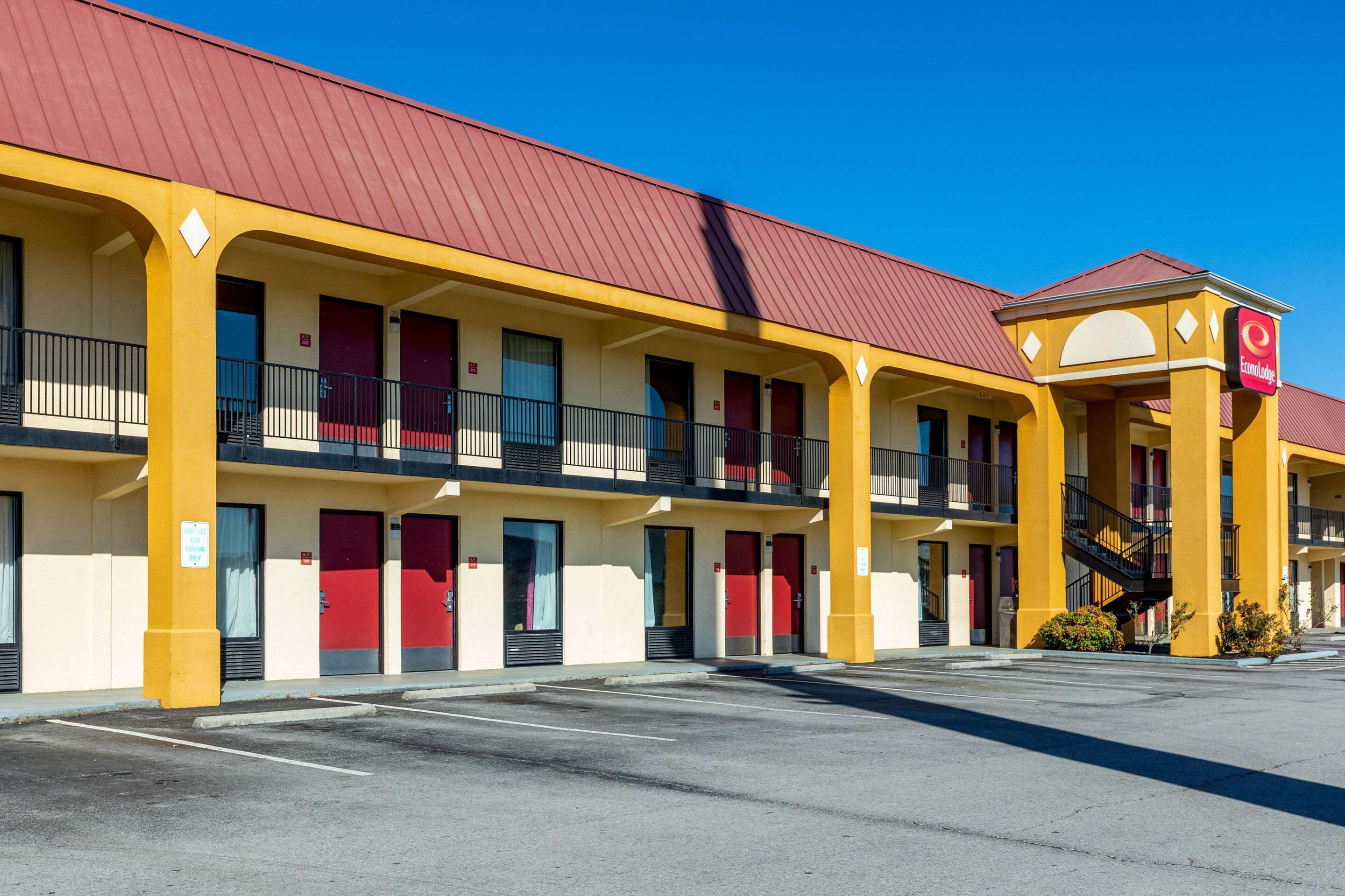 A motel with a red roof, yellow exterior, and multiple balconies.