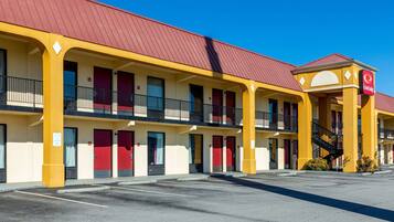 A motel with a red roof, yellow exterior, and multiple balconies.