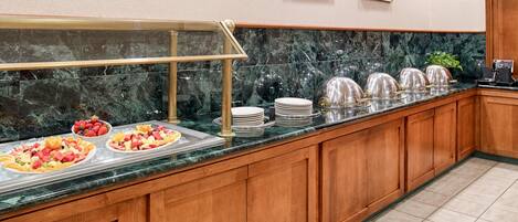 A buffet area with marble countertops, wooden cabinets, and framed artwork on the wall.