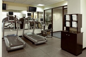 A fitness center with treadmills, exercise bikes, and a cabinet with towels. - Clarion Hotel Portland Airport ME (Portland)