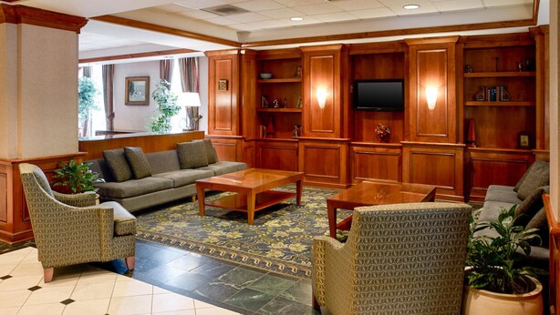 A spacious lobby with a sofa, chairs, a coffee table, and a TV. - Clarion Hotel Portland Airport ME (Portland)