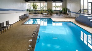 An indoor swimming pool with clear lane markings, a seating area with chairs, and potted plants. - Clarion Hotel Portland Airport ME (Portland)