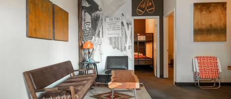 A hallway with a sofa, a chair, a small table, and a ski-themed wall art.