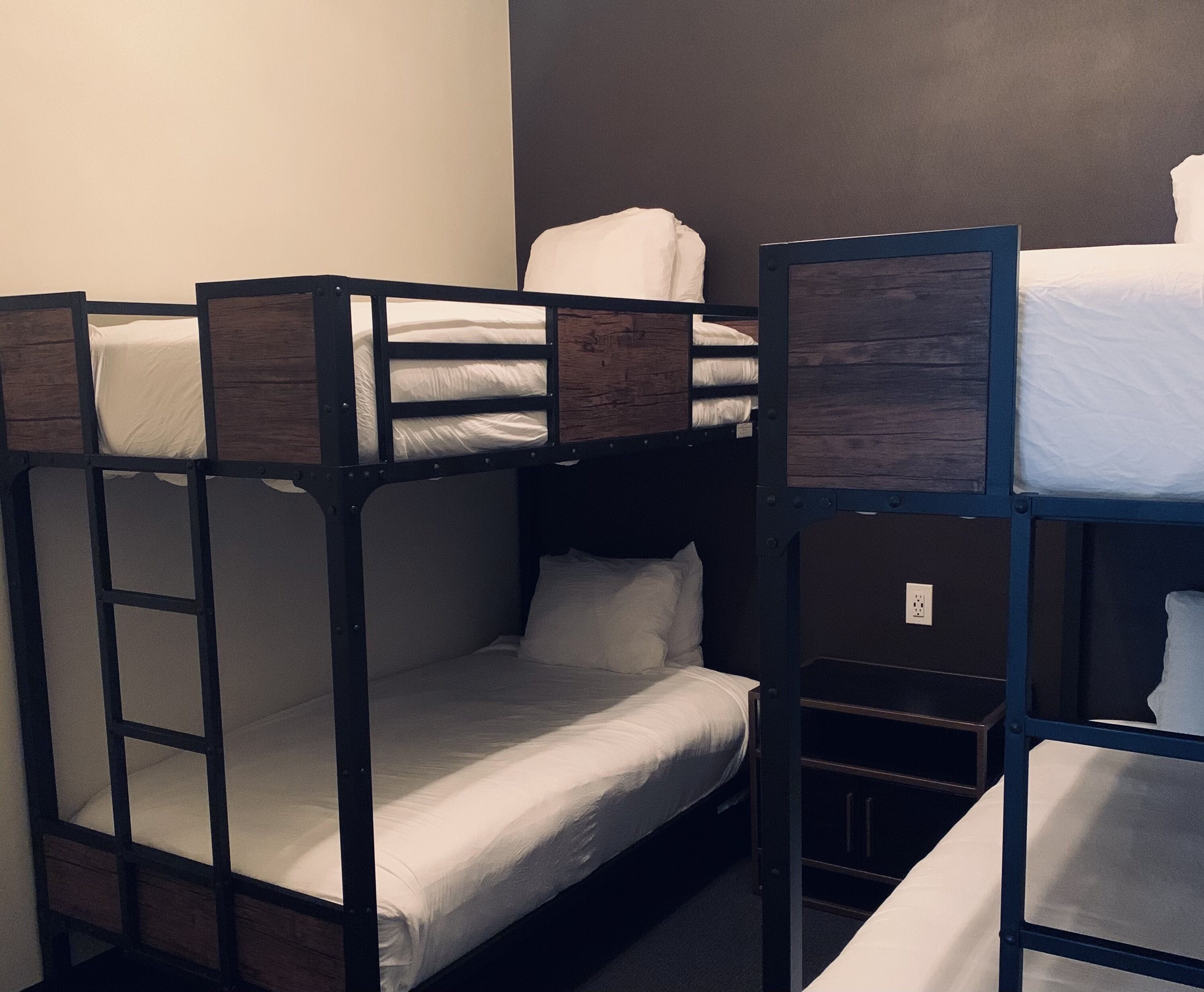 A bunk bed room with a wooden frame and white bedding.