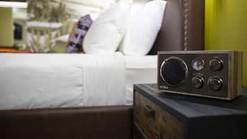 A radio on a wooden nightstand in a hotel room with a bed in the background.