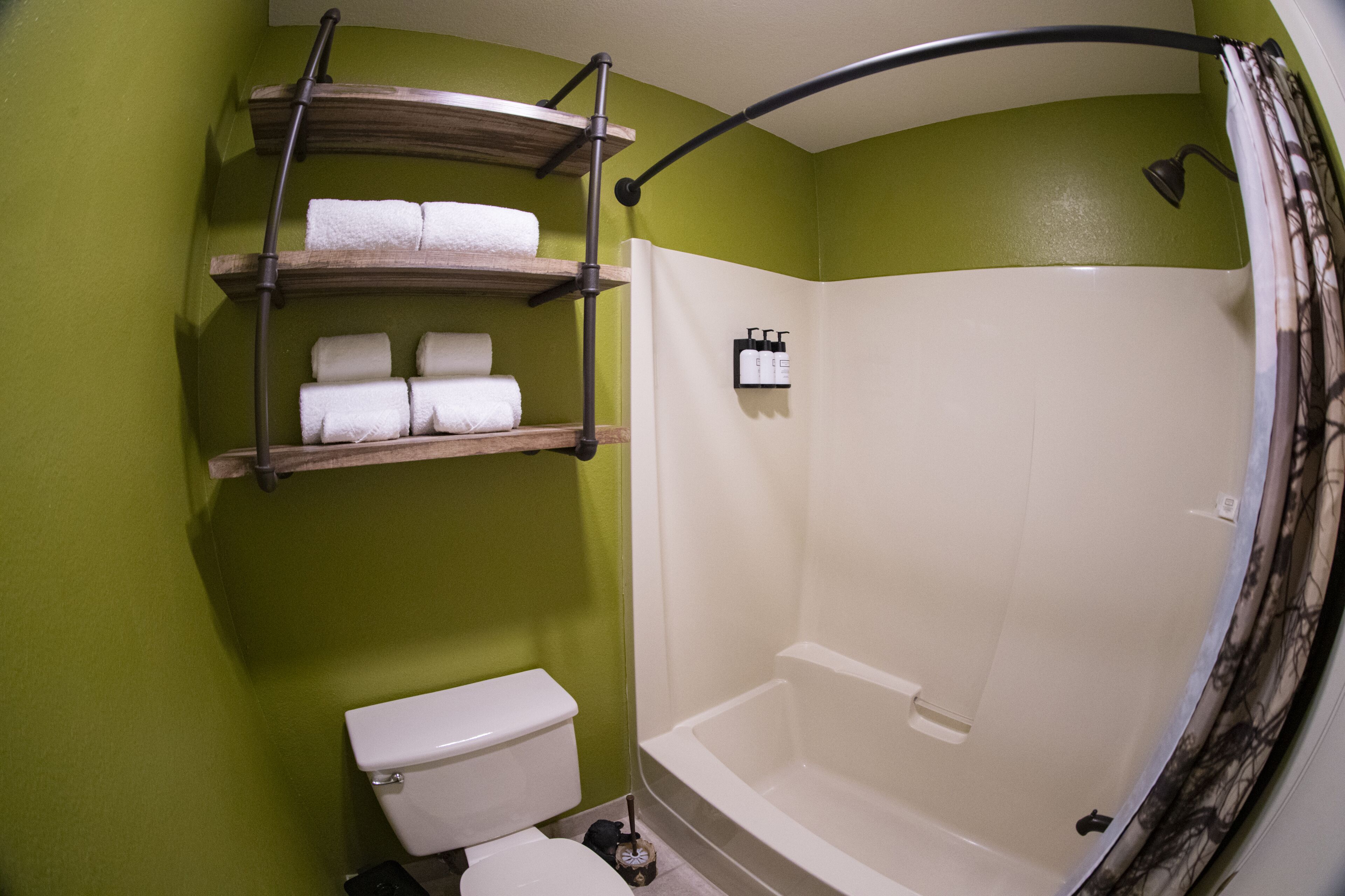 Een badkamer met toilet, bad en planken met handdoeken.