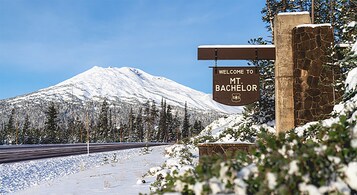 Señal de bienvenida a Mt. Bachelor, con una montaña cubierta de nieve al fondo.