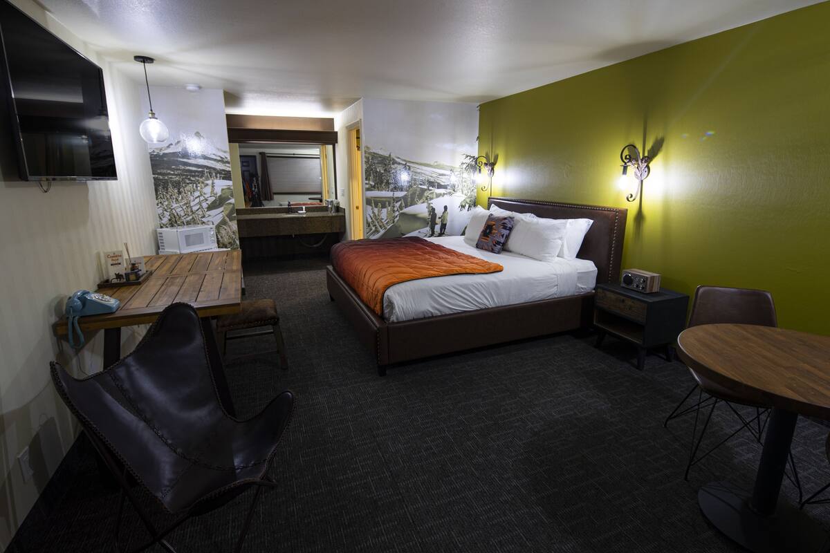 Habitación de hotel con cama, escritorio, silla, mesa, televisor y microondas.